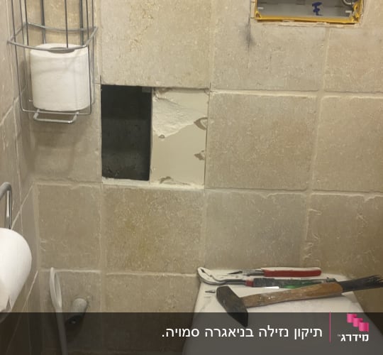 כלי עבודה של אינסטלטור על אסלה וחור בקיר
